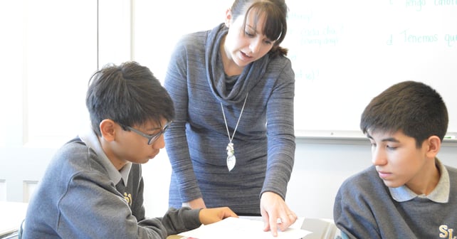 a teacher helping two students with their work